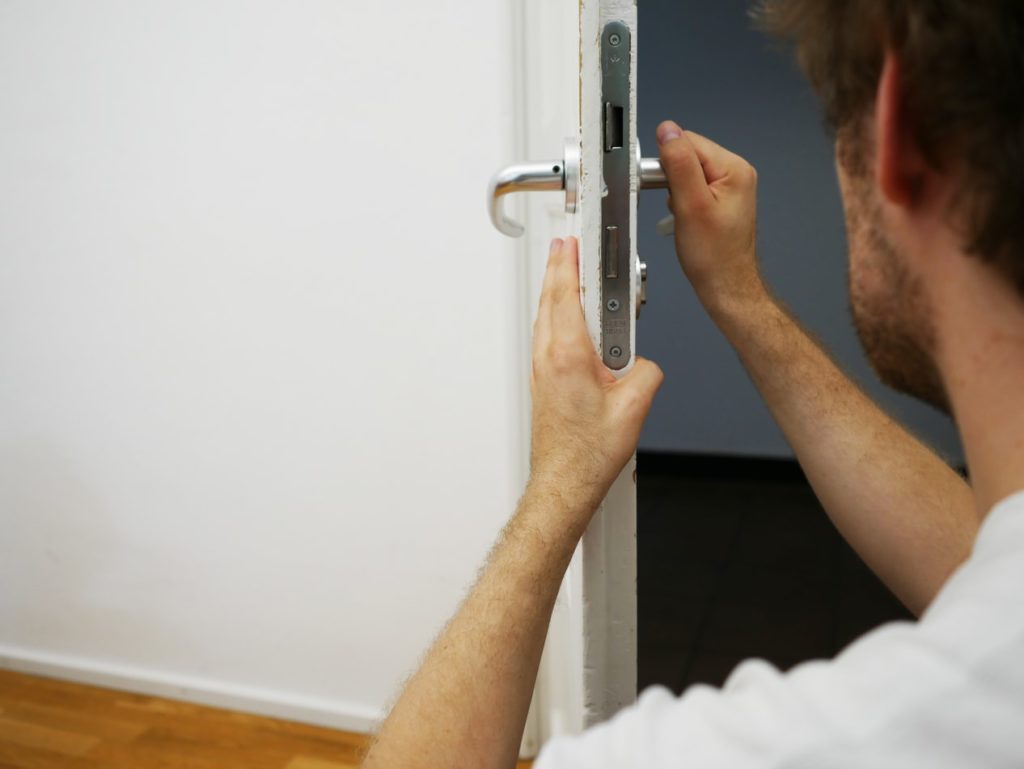 A locksmith installs a lock, one of the common locksmith services